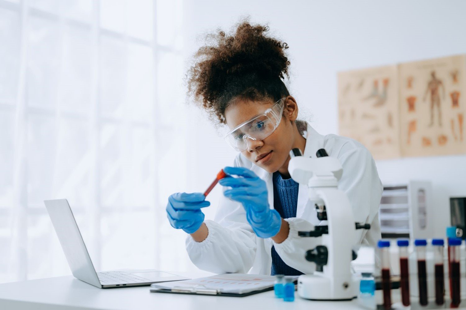 A woman in a lab coat examining a vial.